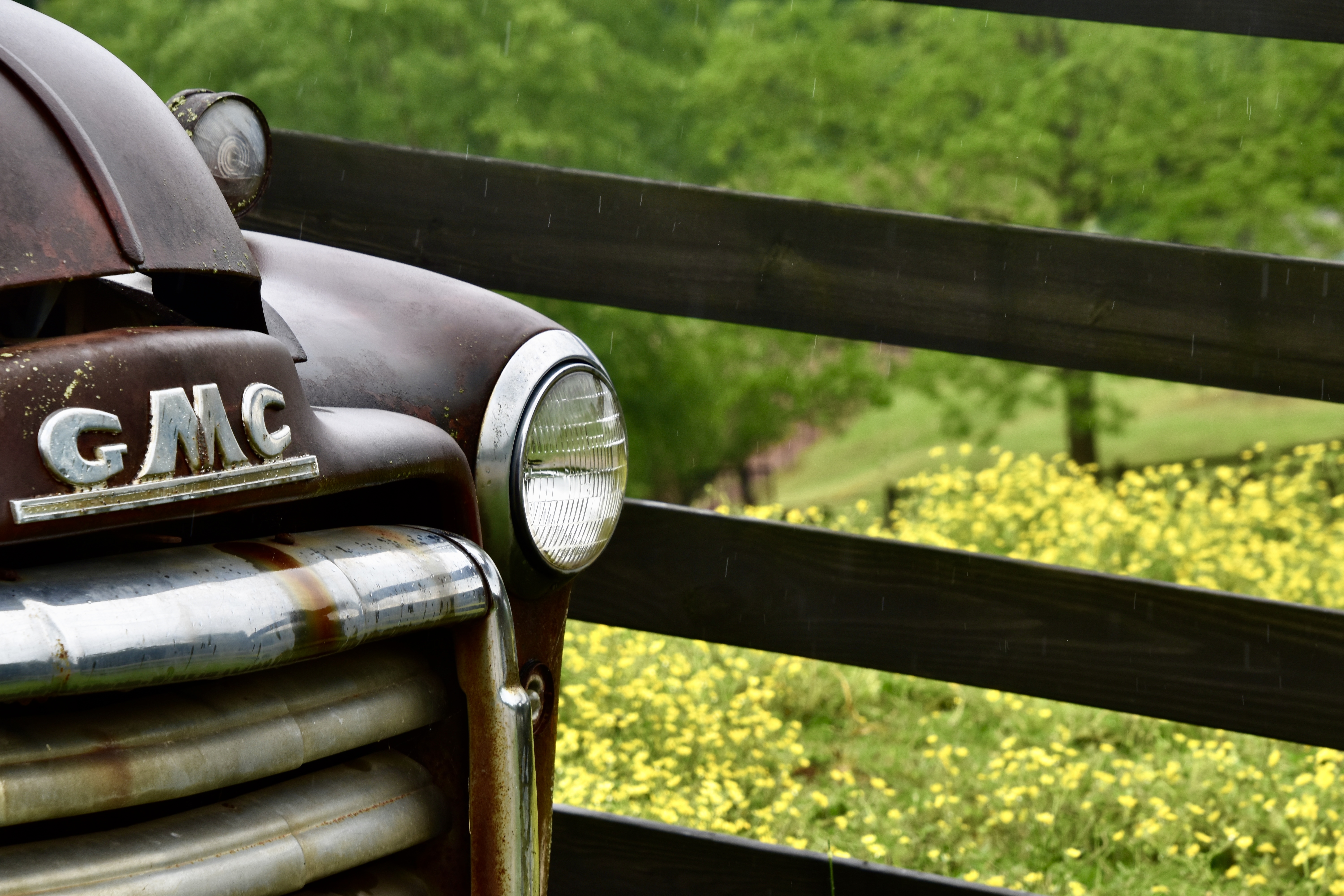 Detail of a vintage GMC truck beside a fence