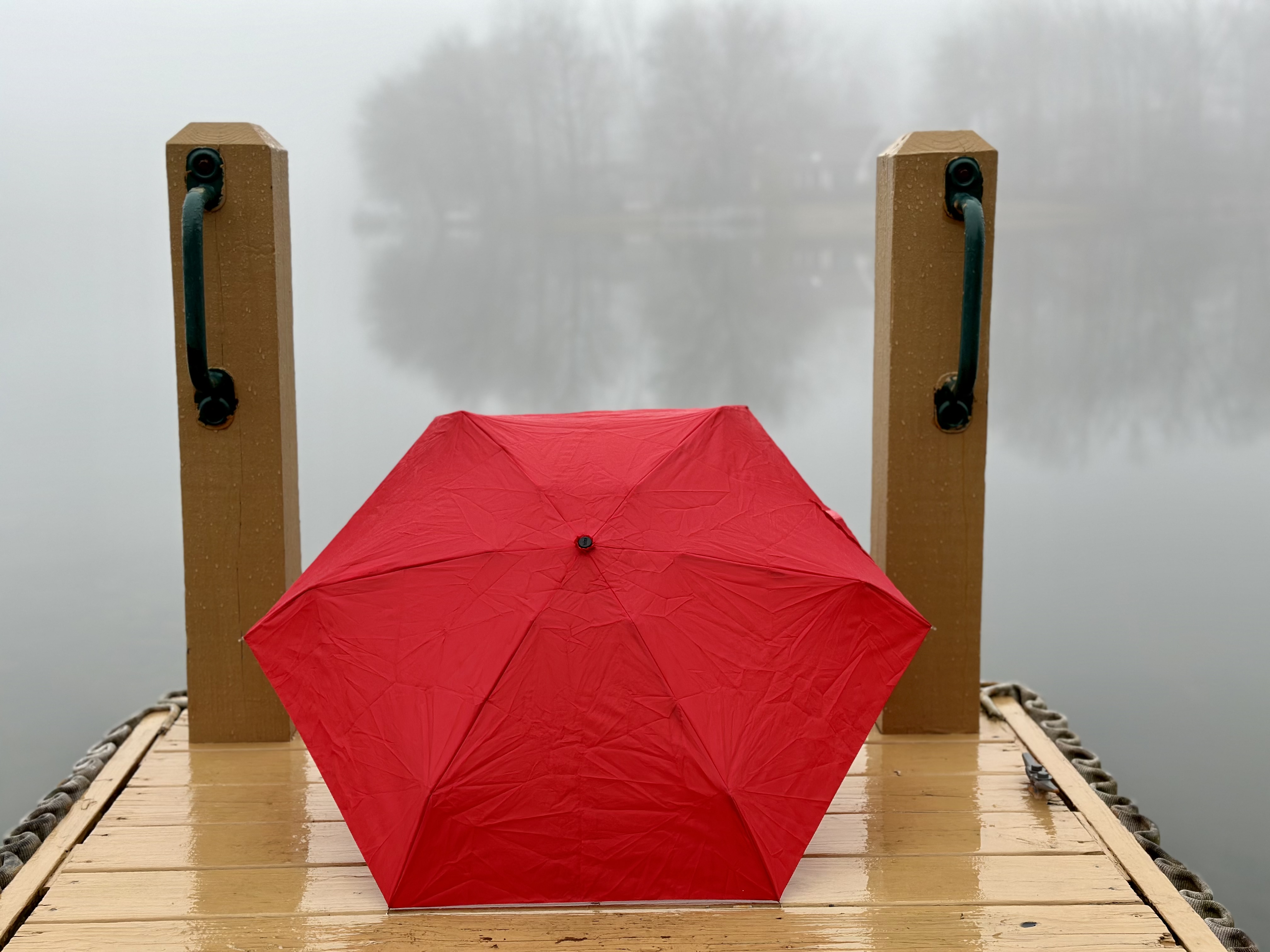 Red umbrella on a foggy dock